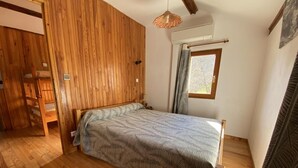 A bedroom with a wooden bed, a window with curtains, and a hanging light fixture. - Holiday Home 'Gîte Le Suquet' with Mountain View and Private Terrace (Dourbies)