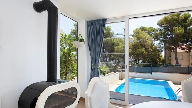 Un balcón con piscina, estufa negra y una silla blanca.