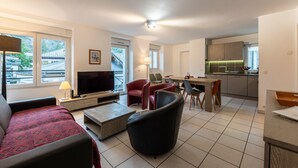 A modern living room with a sofa, TV, and dining area.
