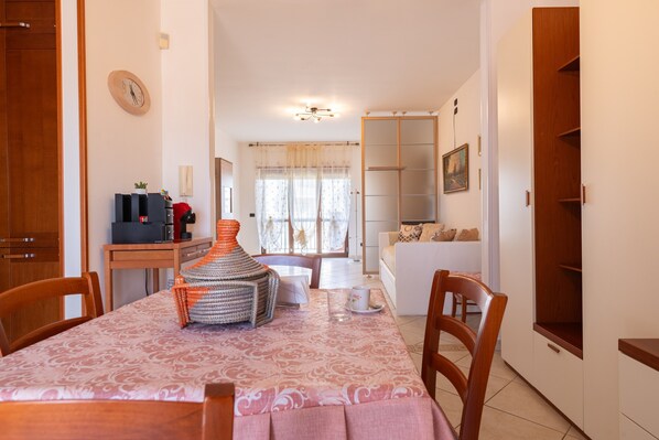 Un coin repas avec une table dressée pour deux personnes, un buffet en bois et une vue sur le salon.
