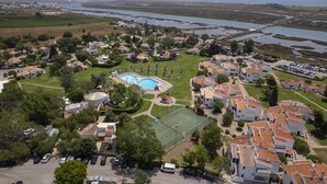 Vue aérienne d’un quartier résidentiel situé sur la côte, avec des maisons, une piscine et un court de tennis.