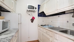Une cuisine de taille réduite avec des meubles blancs, un four à micro-ondes, un grille-pain et un évier.