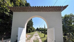 Un arco abierto que da a un sendero de grava rodeado de vegetación.
