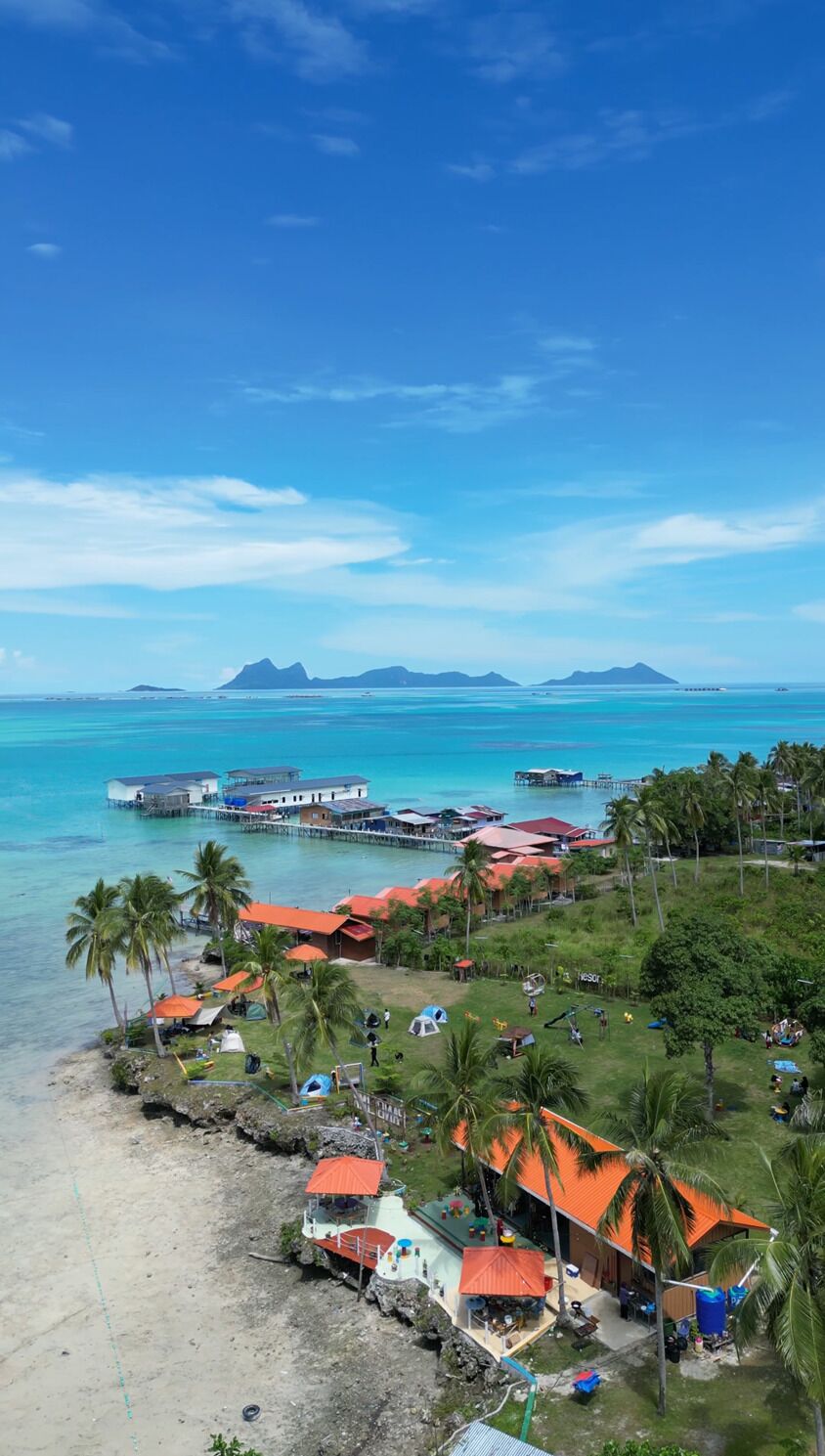 A coastal resort with overwater bungalows, a beach, and palm trees.