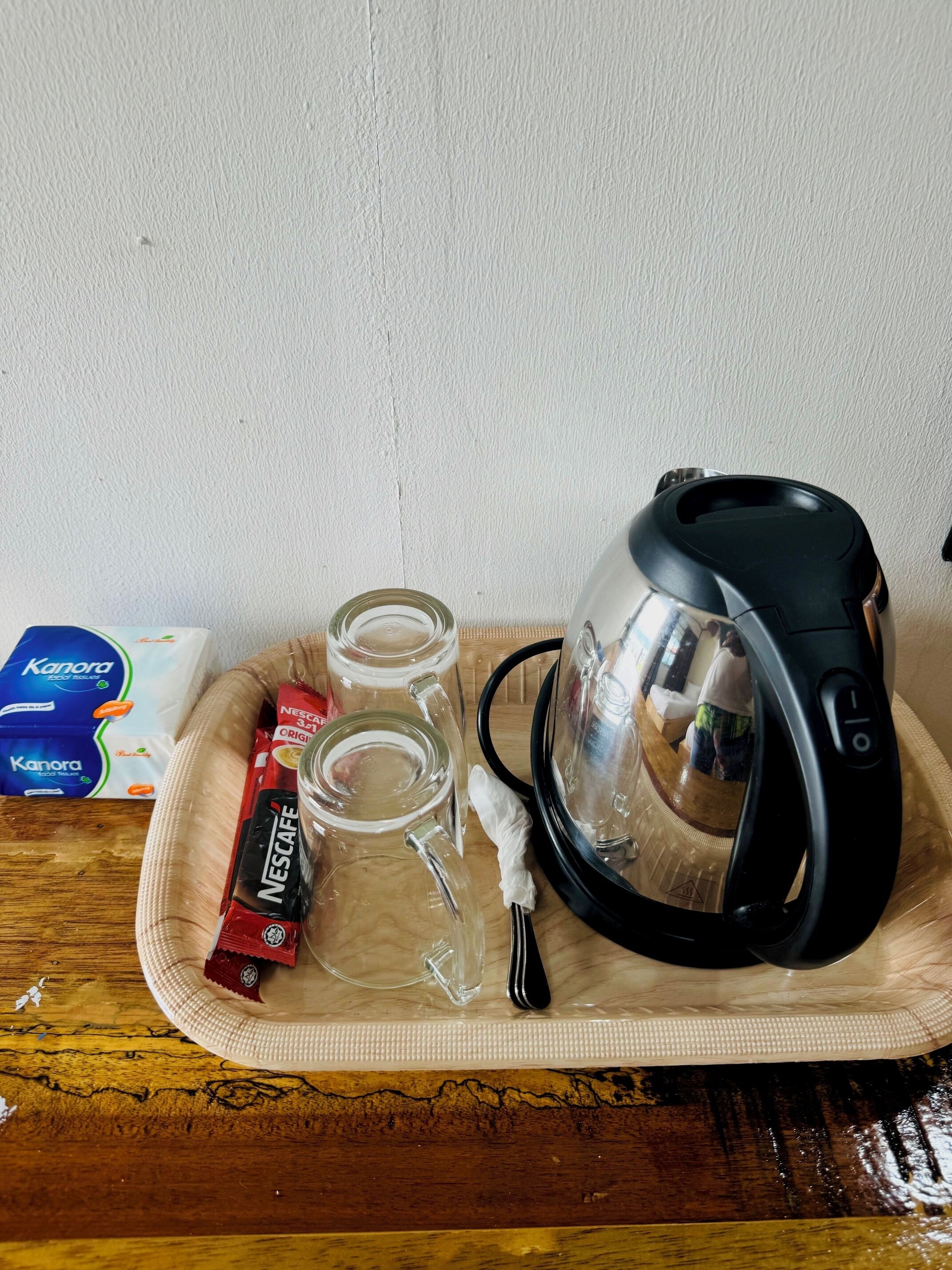 Una safata amb una cafetera, dues copes, un cartutx de cafè Nescafé i una caixa de mocadors Kanora.