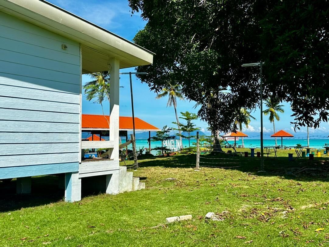 A beachfront property with a light blue building, a covered outdoor seating area, and a view of the ocean.
