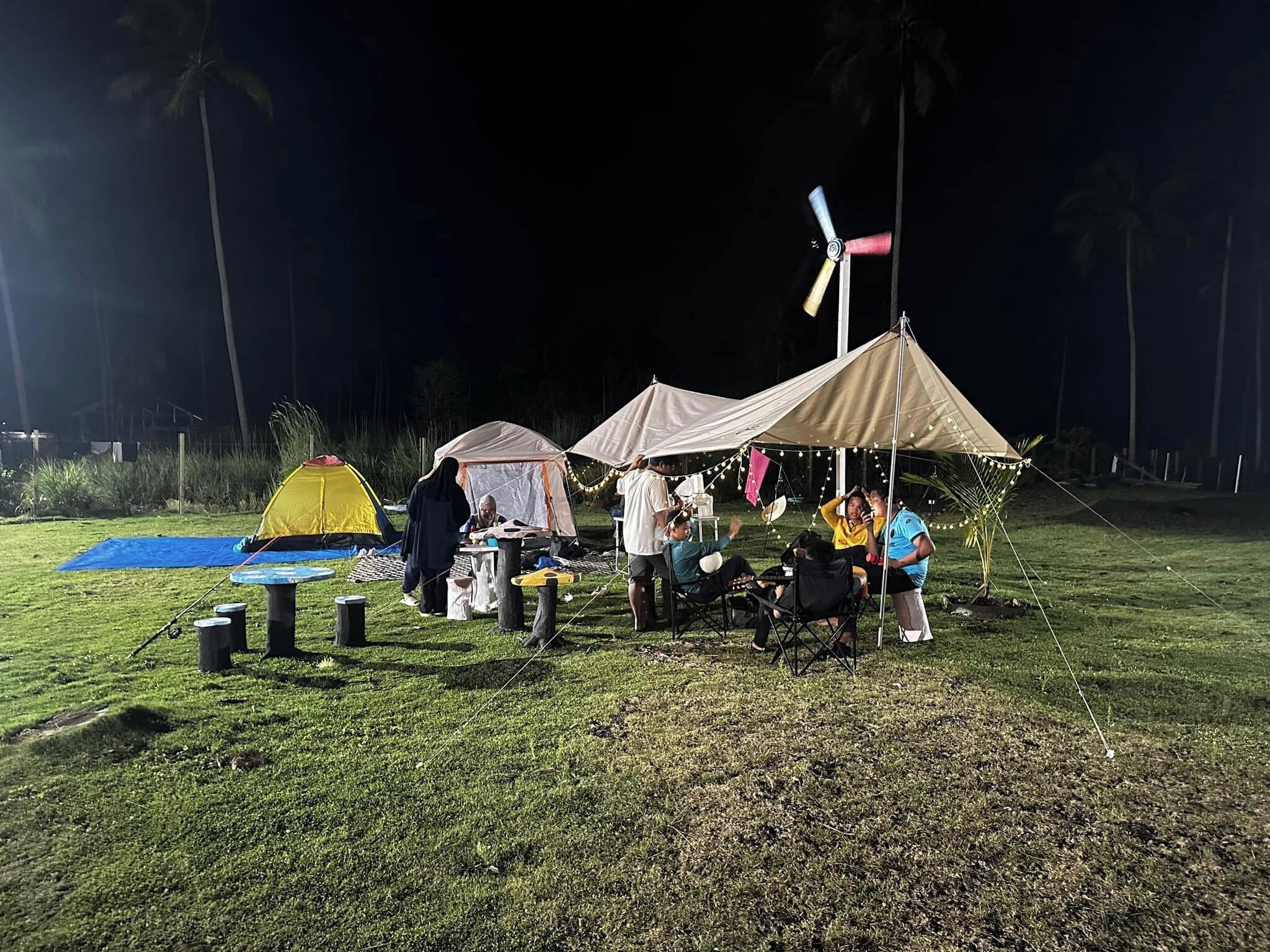 A campsite with tents and a dining table set up under a canopy.