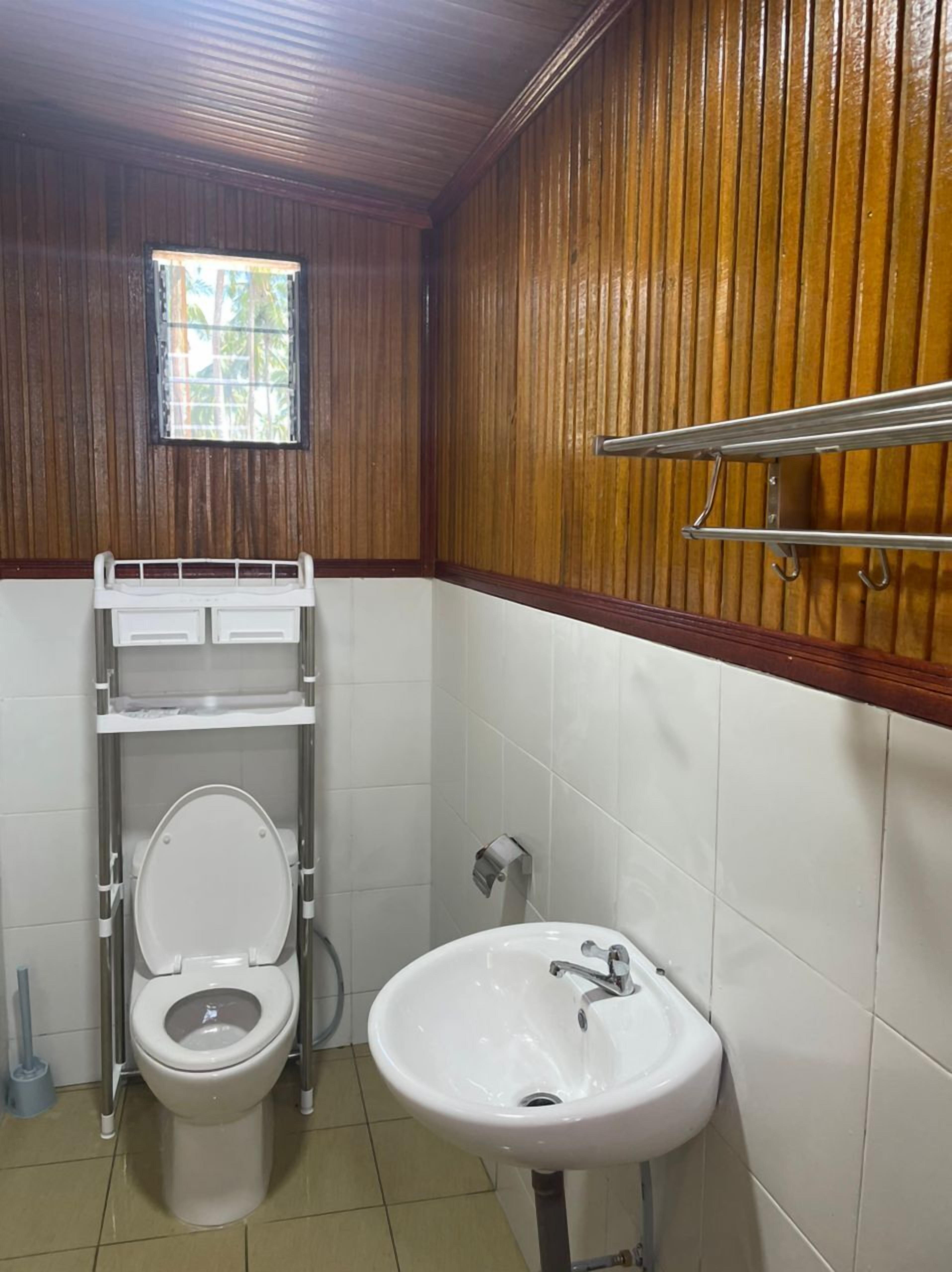 A bathroom with a toilet, sink, and window.