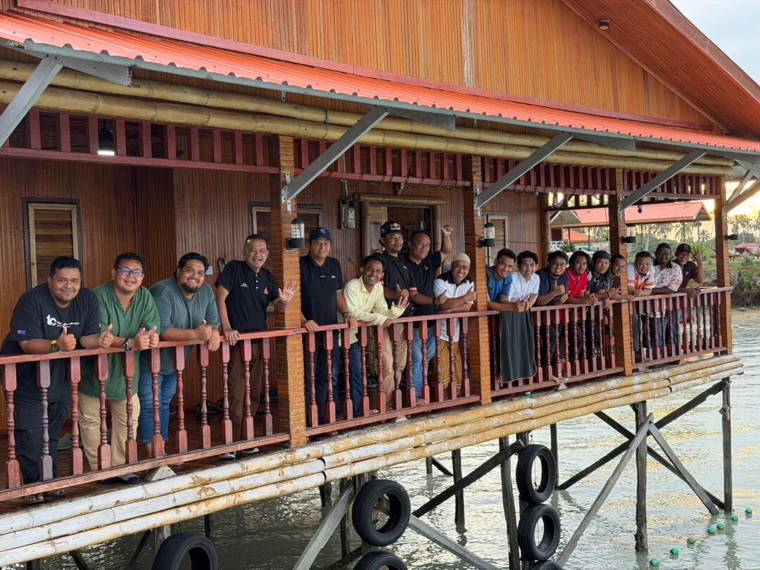 A wooden structure with a balcony, supported by tires, overlooking water.