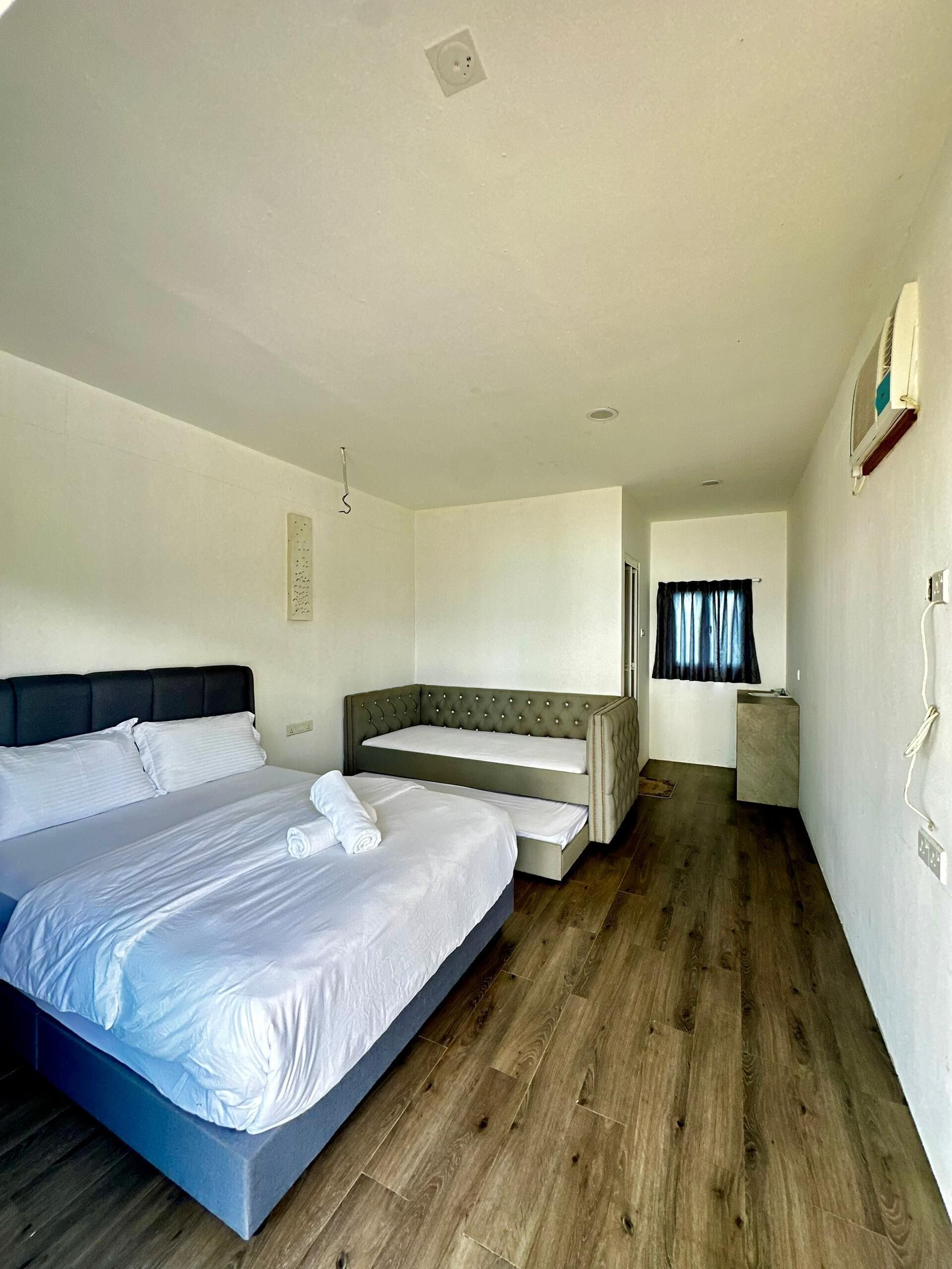 Een slaapkamer met een groot bed, een kleiner bed en een bank.