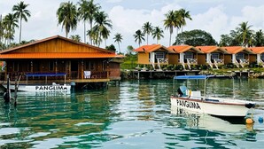 A wooden houseboat with a covered deck and a smaller boat docked nearby. - Panglima Resort Bum Bum Island, Semporna (Bum Bum Island)