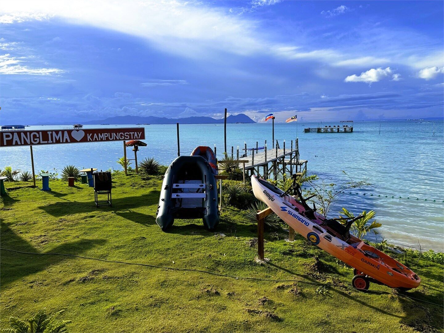 A coastal scene with a sign reading "Panglima Kampungstay," a dock, and a small boat.