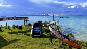 A coastal scene with a sign reading "Panglima Kampungstay," a dock, and a small boat.