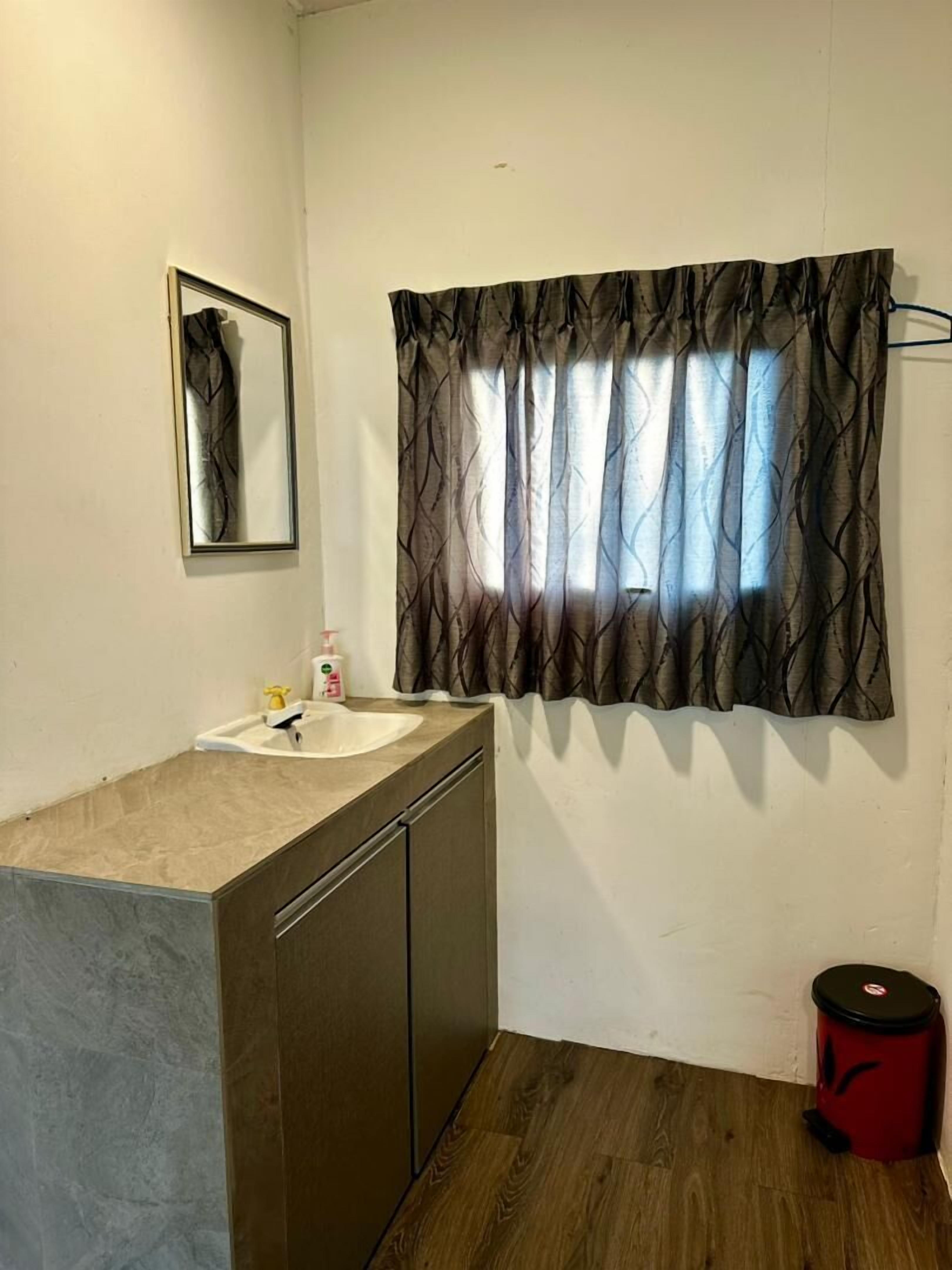 A bathroom with a sink, mirror, and window with curtains.
