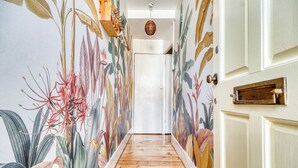 A hallway with a wooden floor and walls adorned with a tropical floral mural.