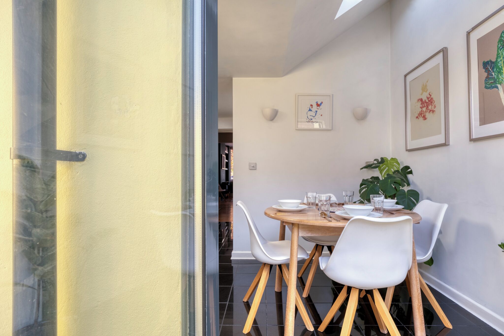 A dining area with a round table, white chairs, and a potted plant.