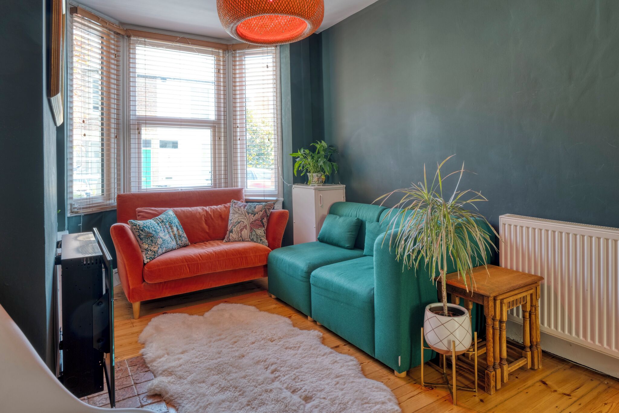 A living room with a red sofa, teal sofa, and a white shag rug.
