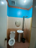 Un baño pequeño con inodoro, lavamanos y ducha.