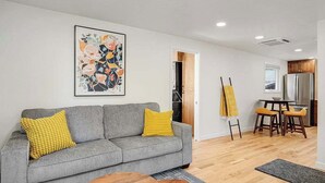 A modern living room with a grey sofa, yellow cushions, a wooden coffee table, and a painting on the wall. - Charming Historical Home in Downtown Boise (Boise)