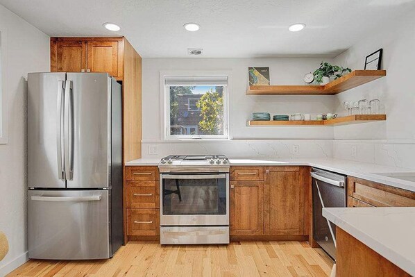 Una cocina moderna con electrodomésticos de acero inoxidable, armarios de madera y un ventanal que proporciona luz natural.