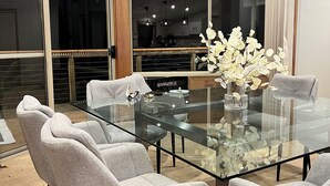 Un coin repas avec une table à plateau en verre, entourée de quatre chaises rembourrées.
