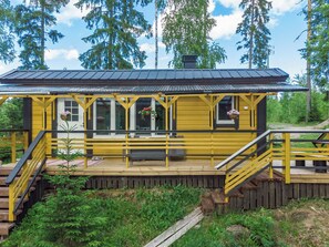 Une cabane en bois jaune dotée d’une terrasse, d’un escalier et d’un porche couvert.