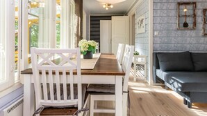 A dining area with a wooden table, white chairs, and a black sofa. - Lammenranta by Interhome (Rautalampi)