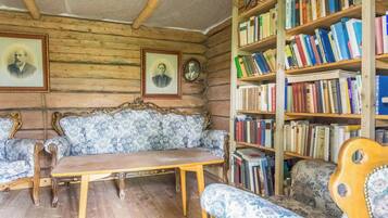 Una stanza con soffitto in legno, un divano, un tavolo e una libreria piena di libri.