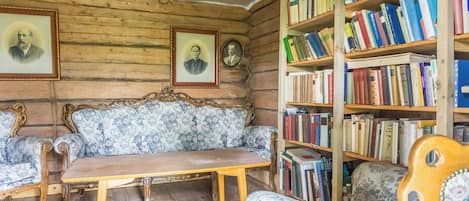 Ein Zimmer mit Holzboden, einem Sofa, einem Tisch und einem Bücherregal voller Bücher.