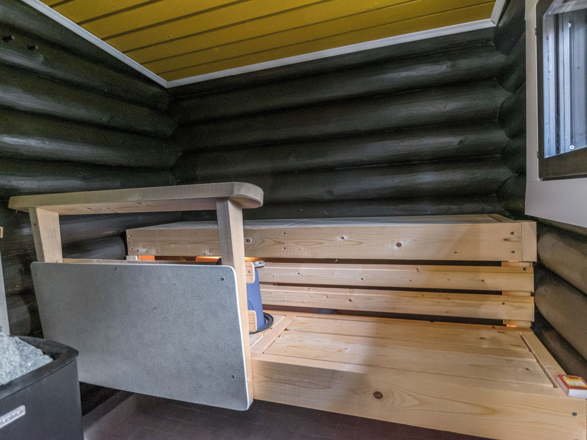 L'intérieur d'une cabane en rondins, avec un banc en bois et une petite table.