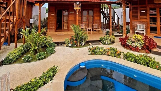 Eine Holzhütte mit Balkon, Pool und einer Pflanzenterrasse.