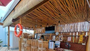 Ein Außenbereich mit Bar, Holzmöbeln und einem Reetdach.