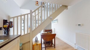 Een trap met witte leuningen die leidt naar een kamer met een houten tafel en stoelen.