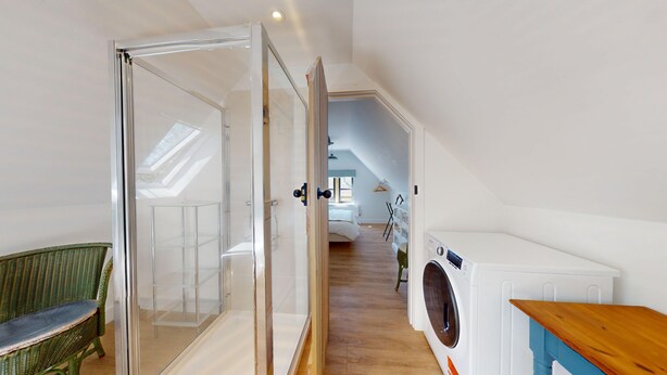 Een moderne, goed verlichte kamer met een glazen deur naar een balkon, een wasmachine en een houten tafel.