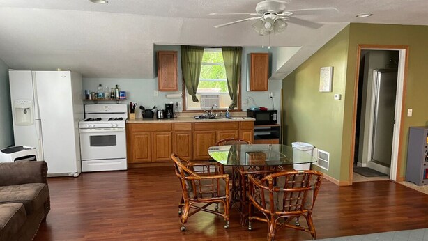 A compact kitchen with a refrigerator, stove, and sink. There is a dining table with chairs in the center. - The Perch- 1 bedroom guest studio above garage (Oregon)