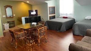 A room with a dining table and chairs, two beds, a TV, and a ceiling fan. - The Perch- 1 bedroom guest studio above garage (Oregon)