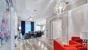 Una sala moderna con piso de madera, un comedor y un sofá rojo brillante.