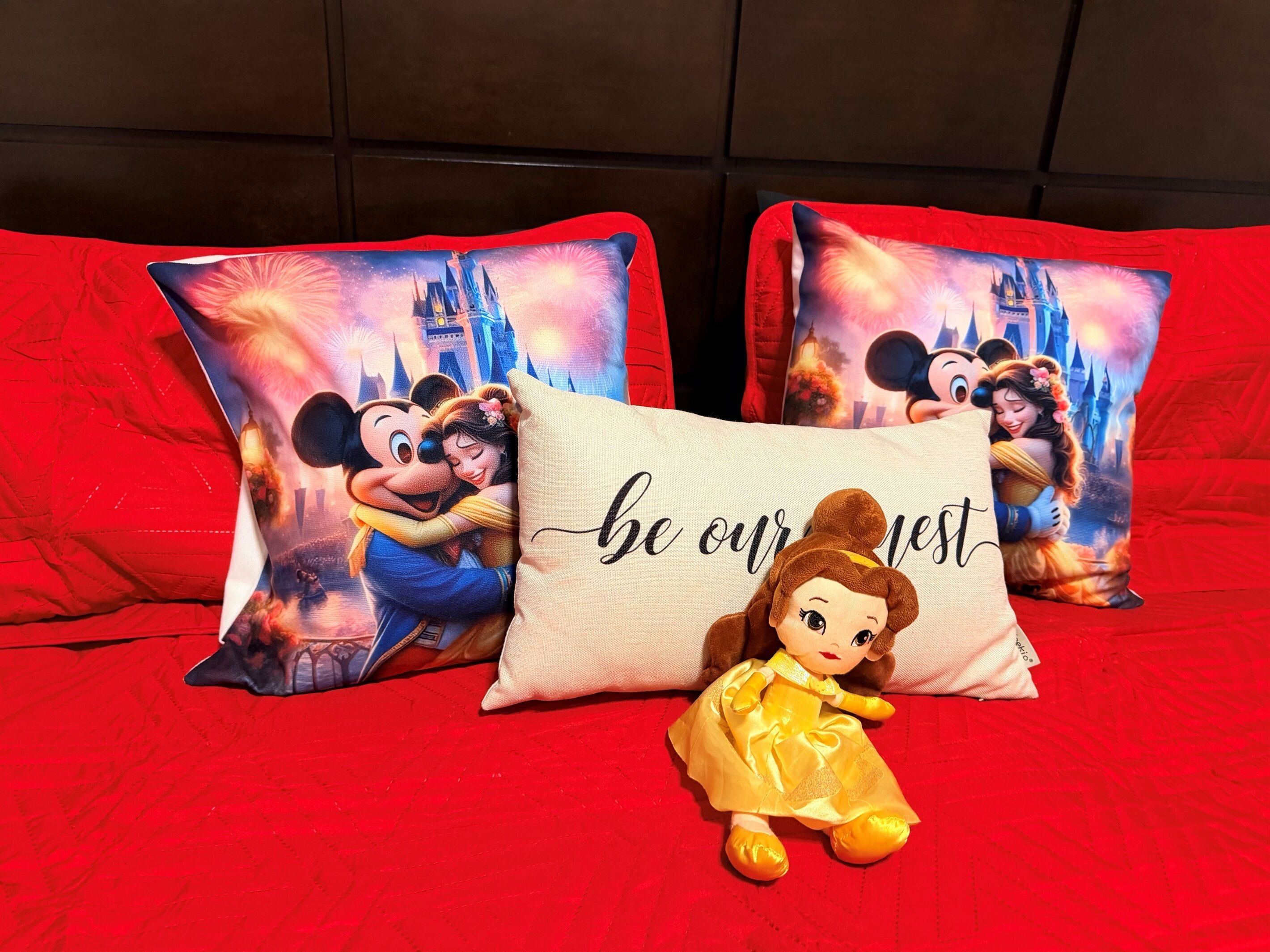 Ein Bett mit roter Bettwäsche und zwei Zierkissen mit Disney-Figuren und der Aufschrift "seien Sie unser Gast".