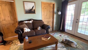 A living room with a brown sofa, a wooden coffee table, and a floral rug. - Quaint, handicap accessible house in serene Lehigh, classified as a ghost town. (Lehigh)