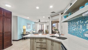 A modern kitchen with a central island, built-in cabinets, and a backsplash with blue mosaic tiles. - Jaco Beachfront Elegance at Tres Regalos Pristine Views in Lovely Jacó Beach (Jacó)