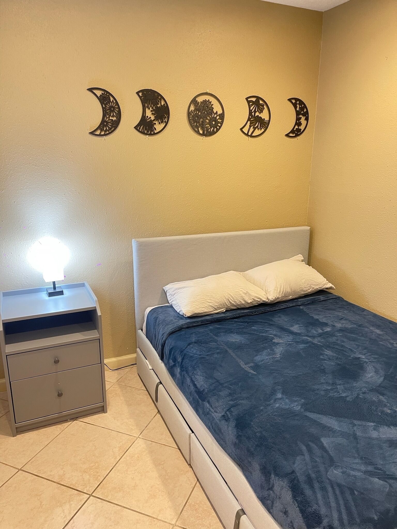 Une chambre à coucher avec un lit, une table de chevet et des œuvres d’art murales.