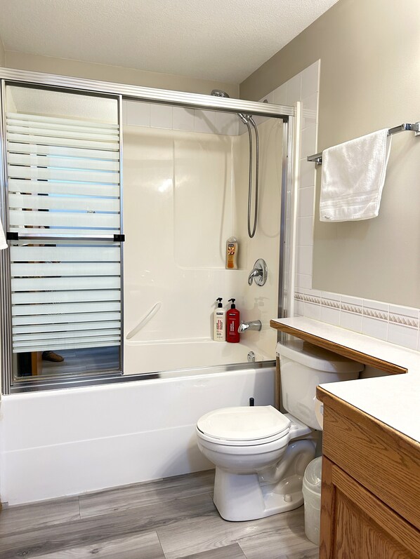 A modern bathroom with a glass-enclosed shower, a toilet, and a vanity with a mirror. - Spacious Cozy Cove Retreat /  6BR / 4BA / 2Kitchen / AC / BBQ (Sylvan Lake)
