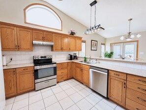A modern kitchen with wooden cabinets, stainless steel appliances, and a large window providing natural light.