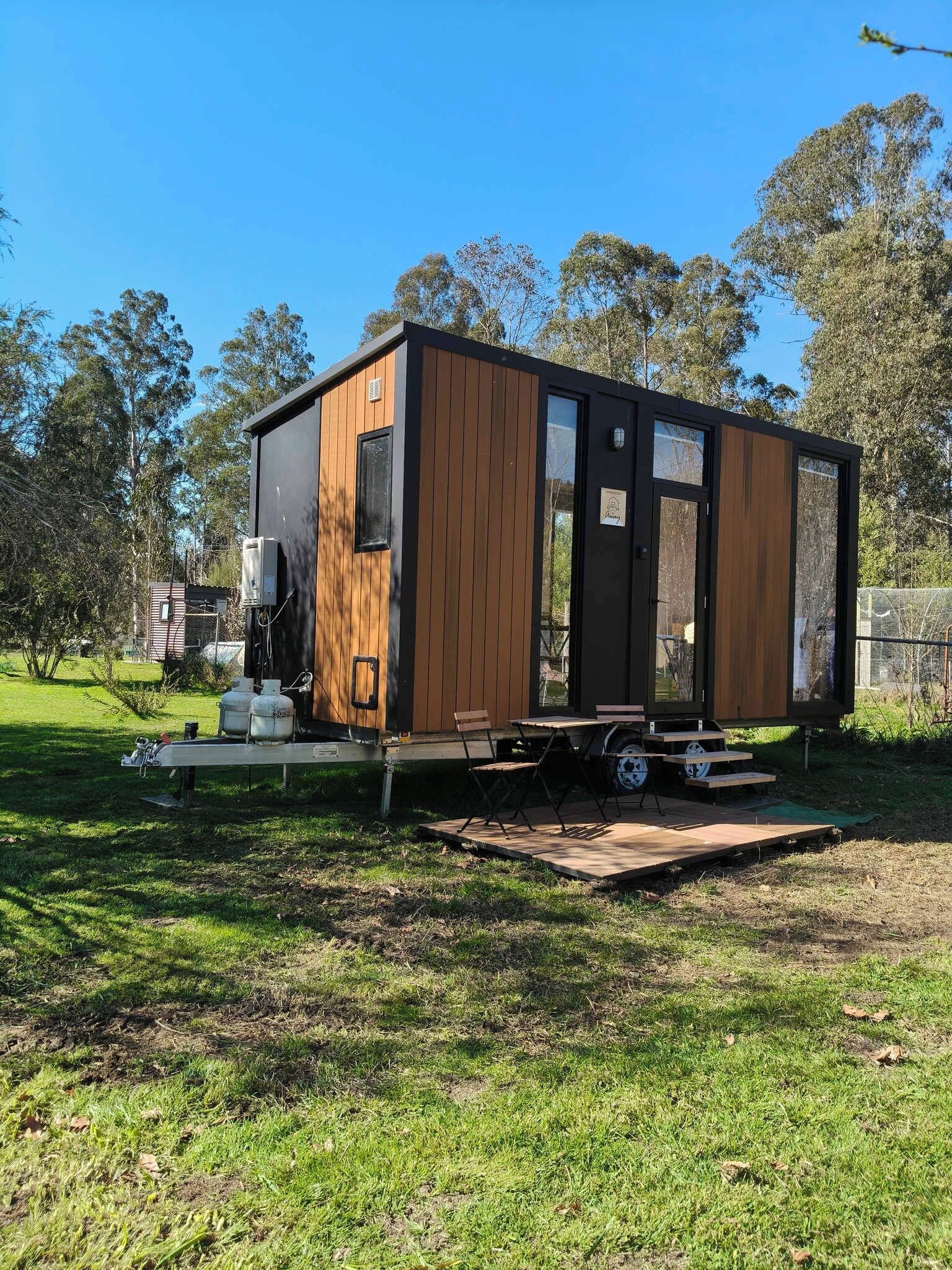 A modern, single-story mobile home with a wooden exterior and large windows.