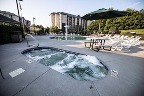 Un espace piscine d’hôtel comprenant des bains à remous, des chaises longues et des parasols.