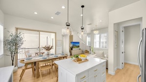 A modern kitchen with a central island, wooden dining table, and pendant lighting. - Brand New Grand Luxury Designer Home in Irvine with Pool & Amenities (Irvine)