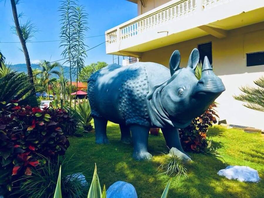 Une grande statue d’éléphant bleu dans un jardin, avec un bâtiment en arrière-plan.