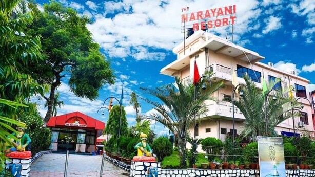 The Narayani Resort with a red entrance, palm trees, and a clear blue sky. - The Narayani Resort (Gaindakot)