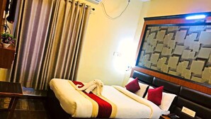 A hotel room with two beds, a wooden headboard, a bedside table with a lamp, and a wall-mounted air conditioner. - The Narayani Resort (Gaindakot)