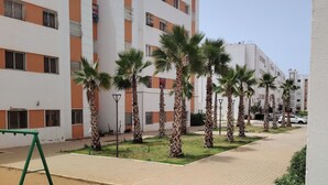 Un edificio residenziale con diversi balconi, un vialetto lastricato e palme.